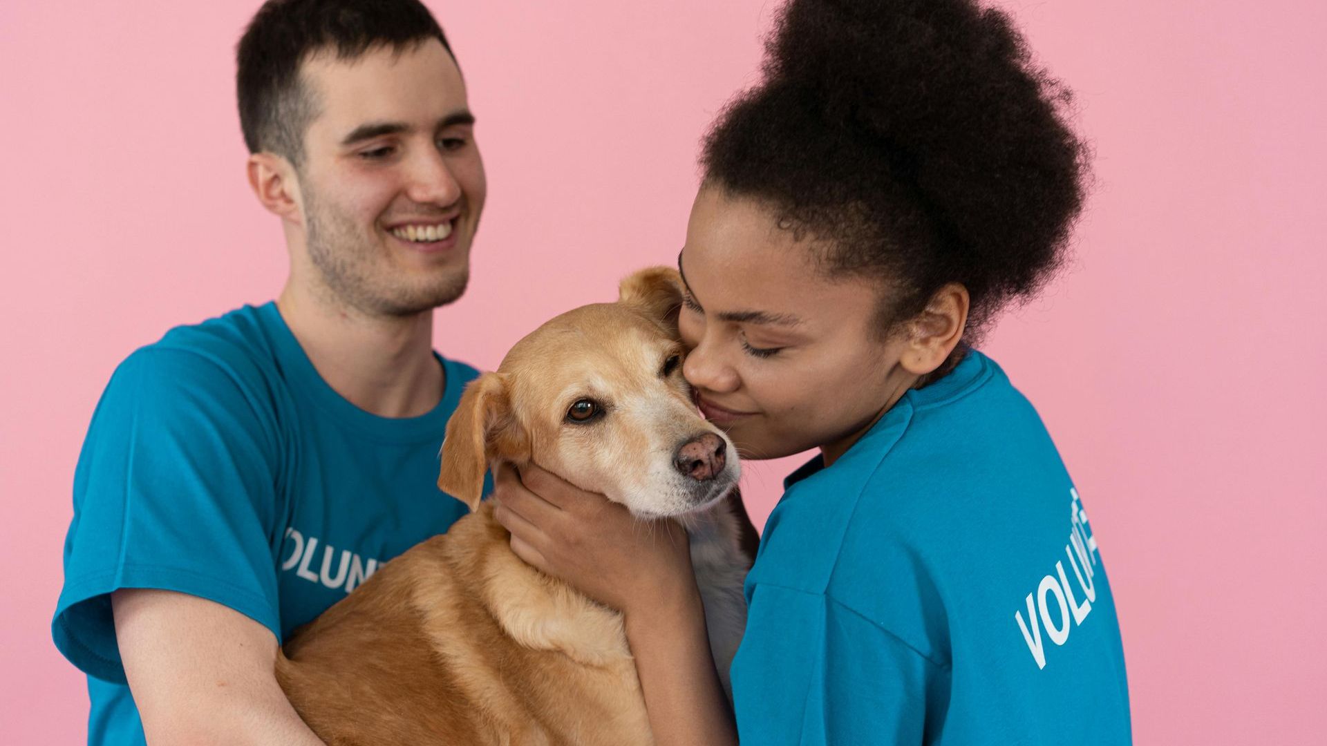 Image of one male and one female volunteer hugging a dog.