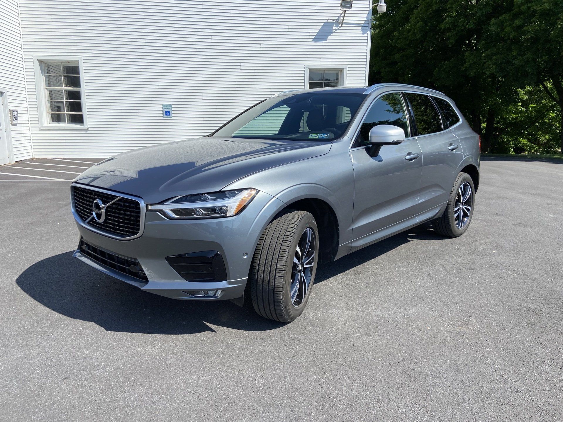 A gray volvo xc60 is parked in front of a white building.