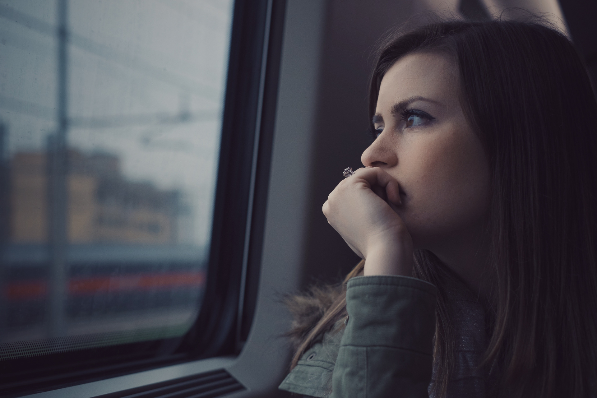 A woman is looking out of a train window.