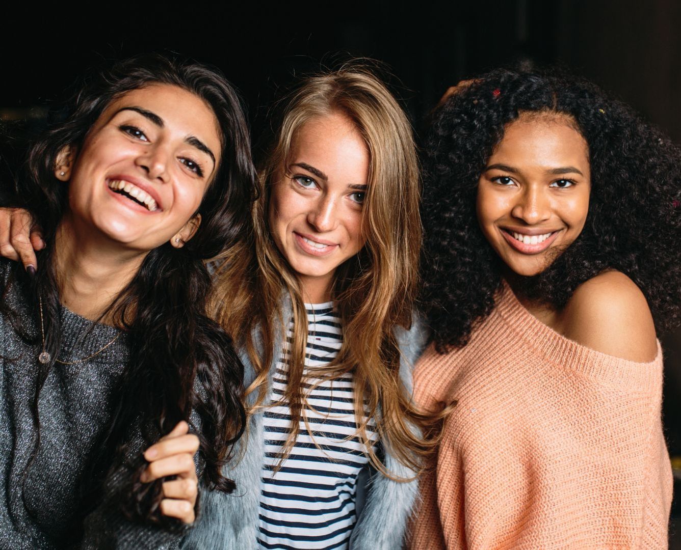 Three women are posing for a picture together and smiling.