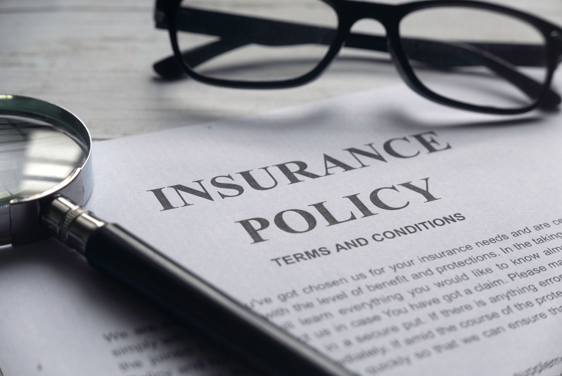 Close-up of an insurance policy document, from a business insurance agency, with glasses on top.