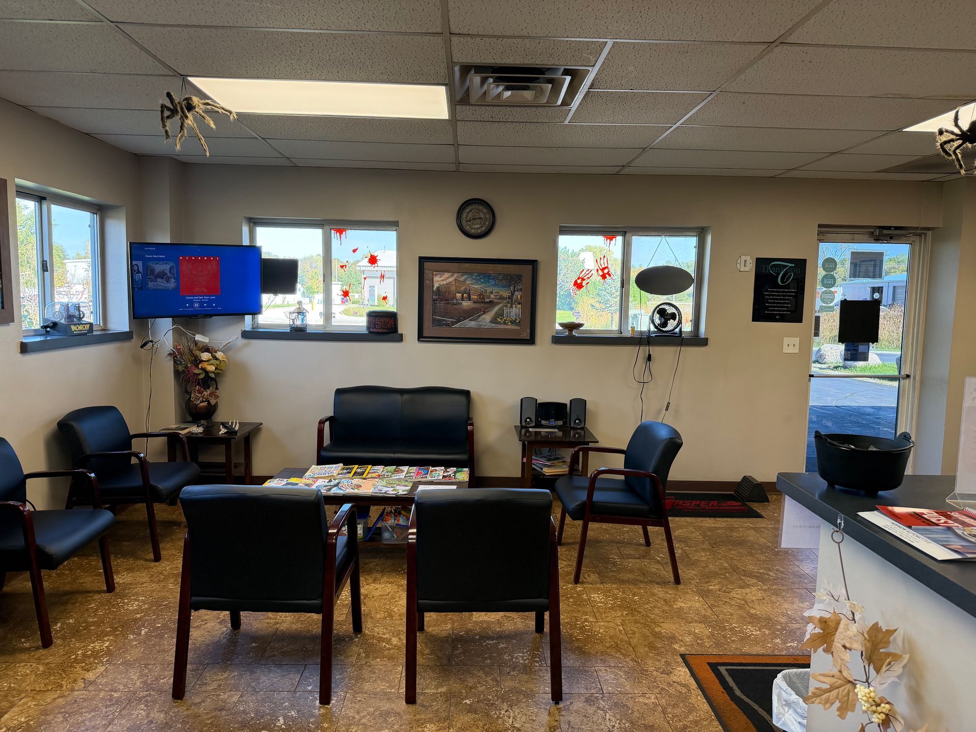 Waiting room with chairs, sofa, small table, wall decor, and a TV. | Hopson Automotive