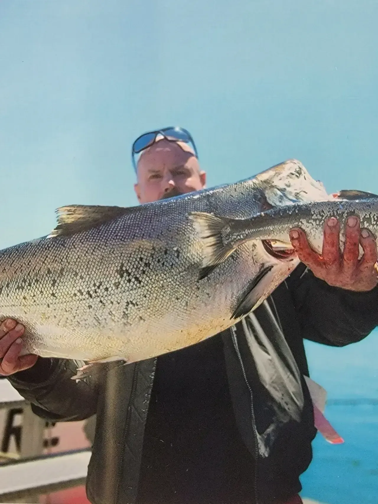 A Man is Holding a Large Fish in his Hands