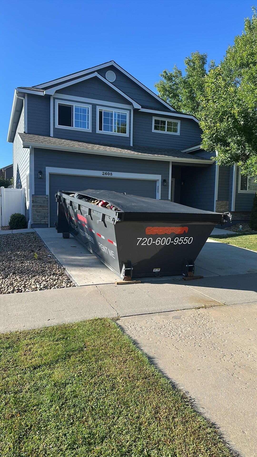 White flatbed tow truck on a dirt road in front of a mountain with evergreen trees.