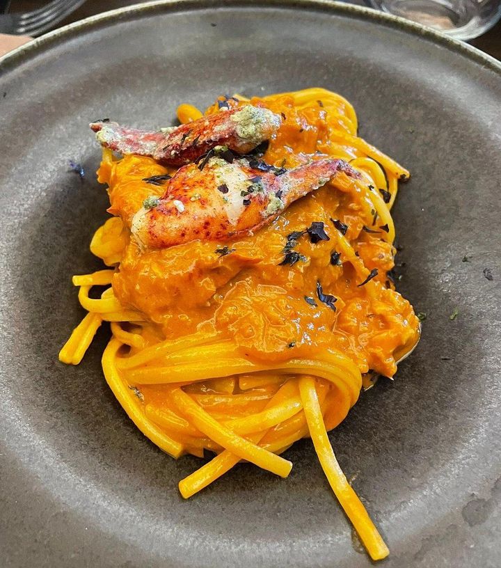 Pasta con salsa all'arancia e formaggio grattugiato su un piatto scuro