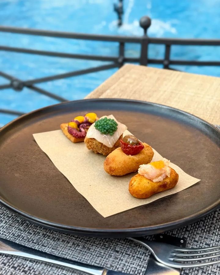 Un assortimento di dessert su un piatto a bordo piscina, con quattro pasticcini monoporzione su un tovagliolo di carta.