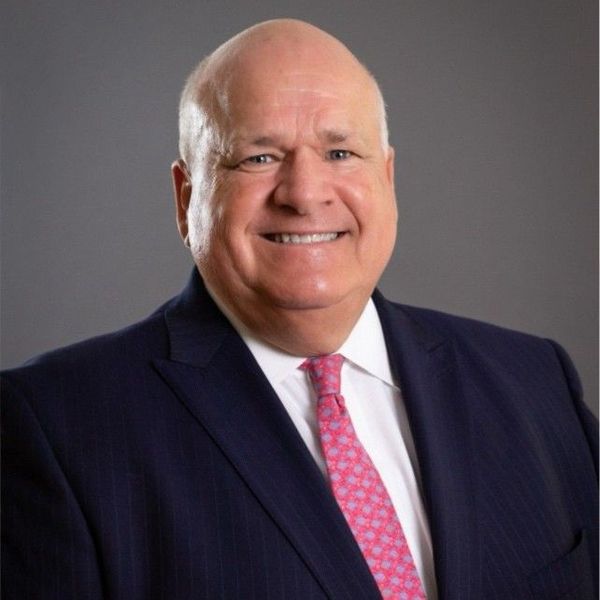 A man is holding a dog in his arms and the dog is wearing a sweater.