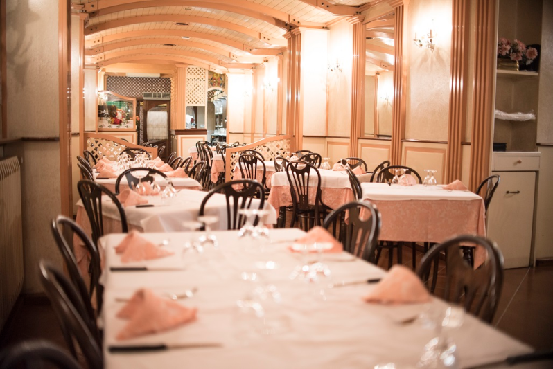 Sala da pranzo del ristorante con tavoli apparecchiati per gli ospiti, luci calde e pannelli in legno.