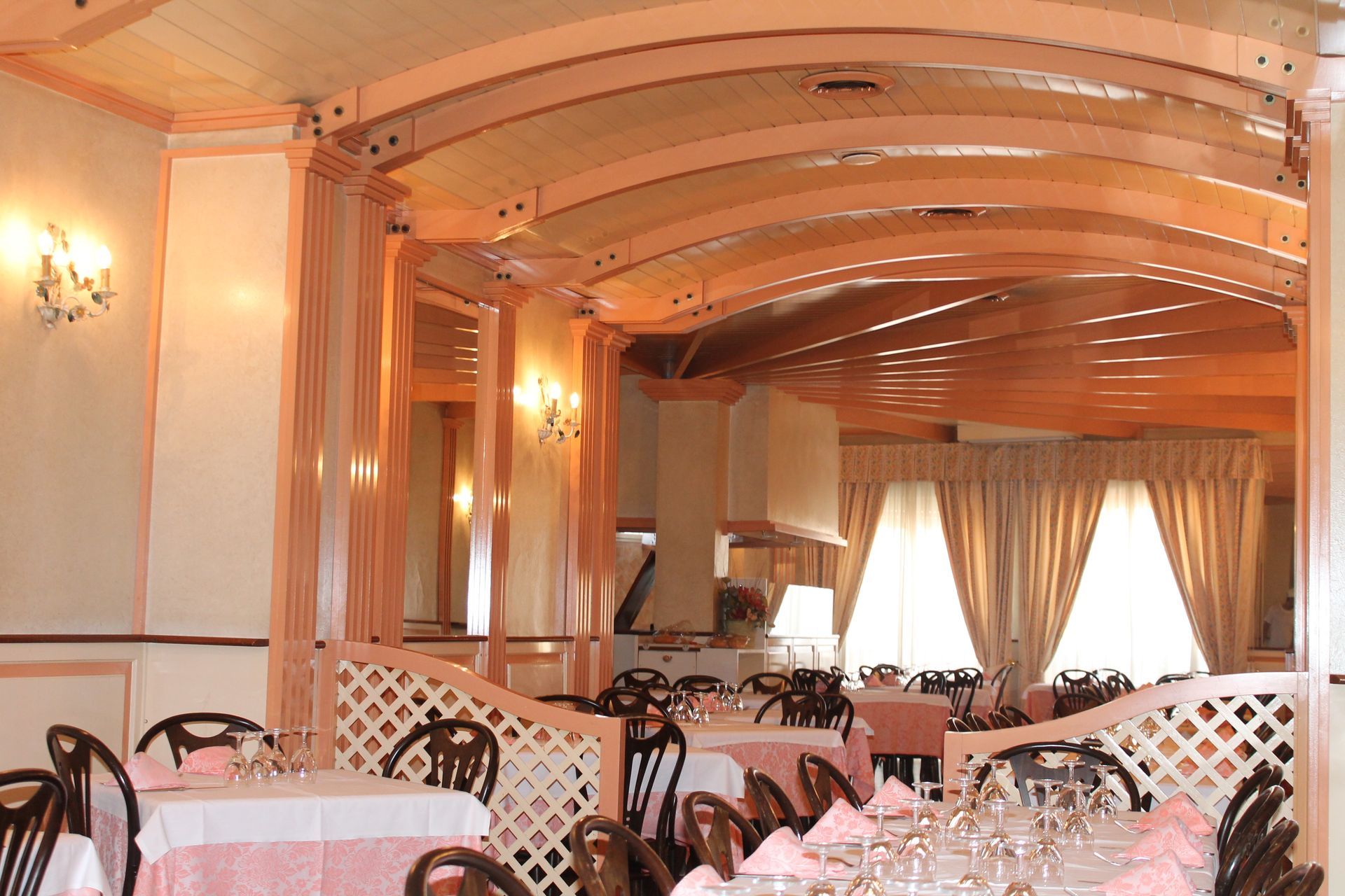 Elegante ristorante con interni in tonalità rosa e crema, tavoli apparecchiati e soffitto a volta.