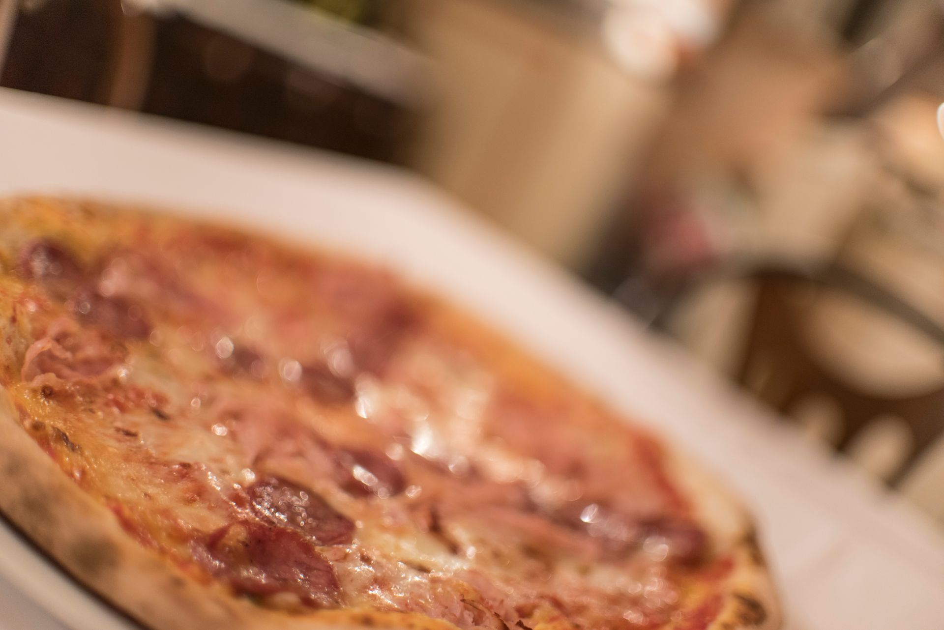 Pizza su un tavolo bianco, leggermente sfocata, in un ambiente da ristorante.
