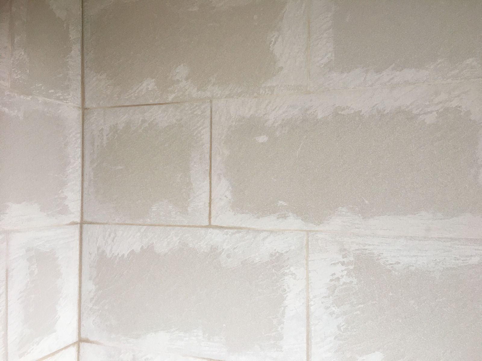 A close up of a drywall wall with a lot of holes in it.
