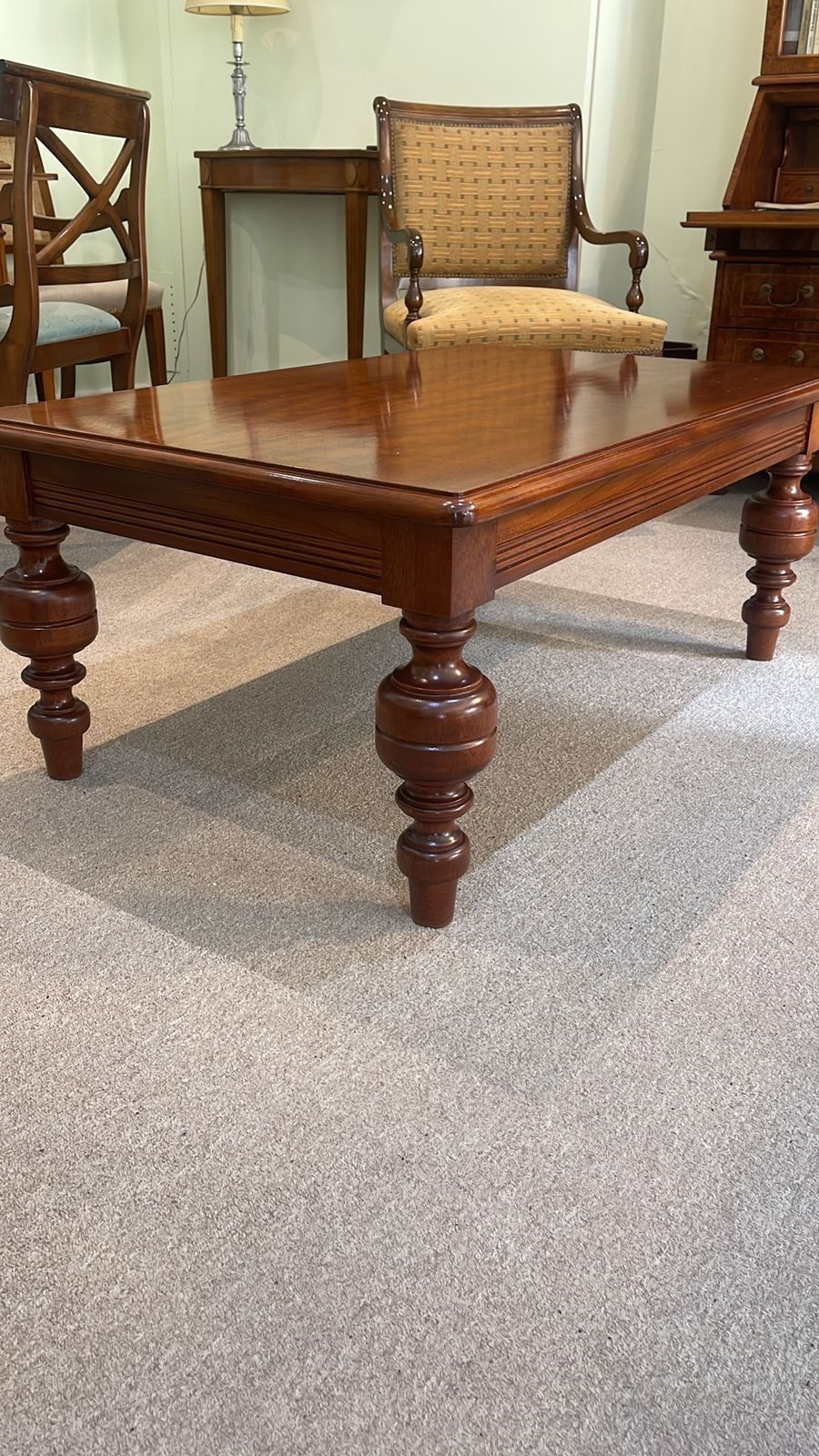 Una mesa de café de madera está colocada sobre un piso alfombrado en una sala de estar.