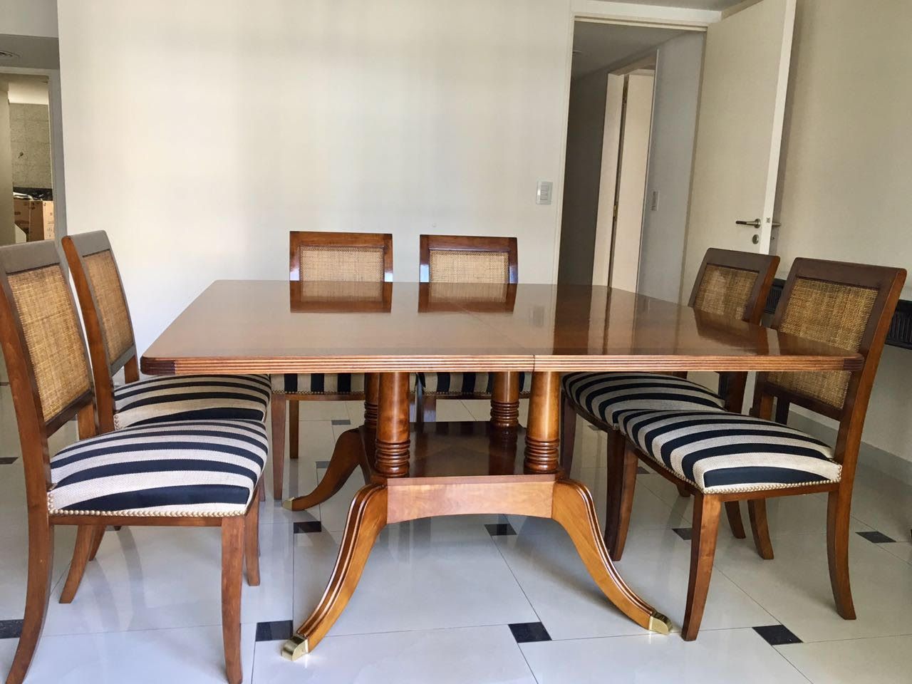 Una mesa de comedor de madera con sillas a rayas en una habitación.