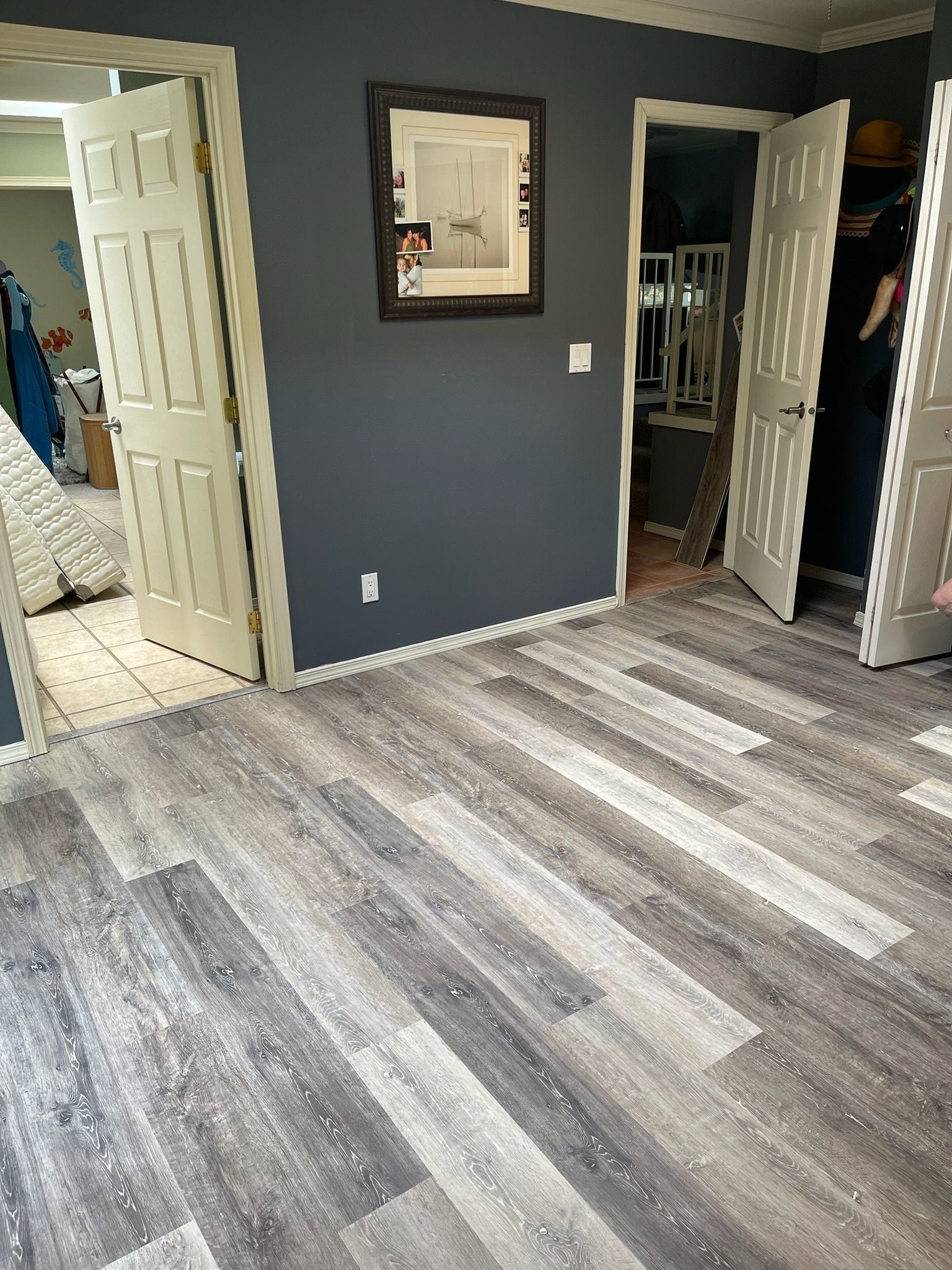 A room with dark gray walls, white trim, wood-look flooring, and two open doorways.