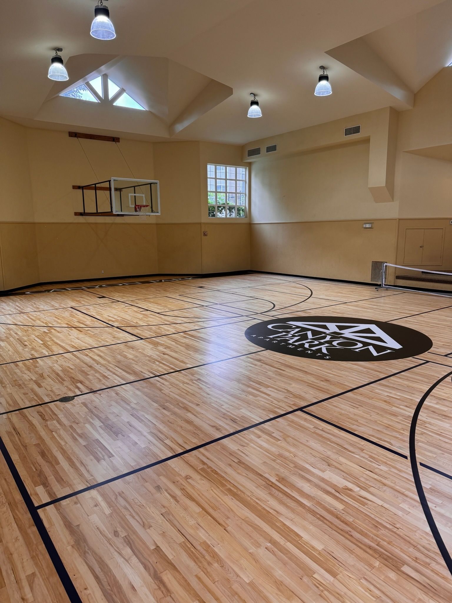 A person in a brown jacket stands with their back to the camera, looking out at a wavy, misty ocean from a stone wall.
