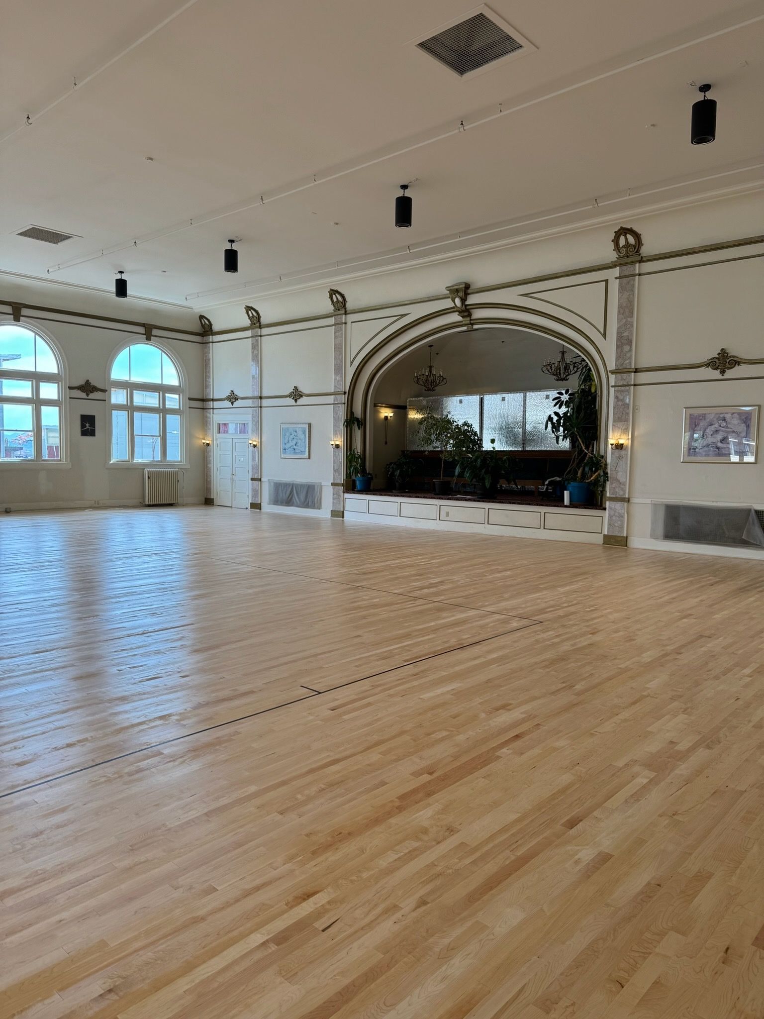 A black wood-burning stove with a fire inside sits on a floor hearth, next to a log holder in a bright living room.
