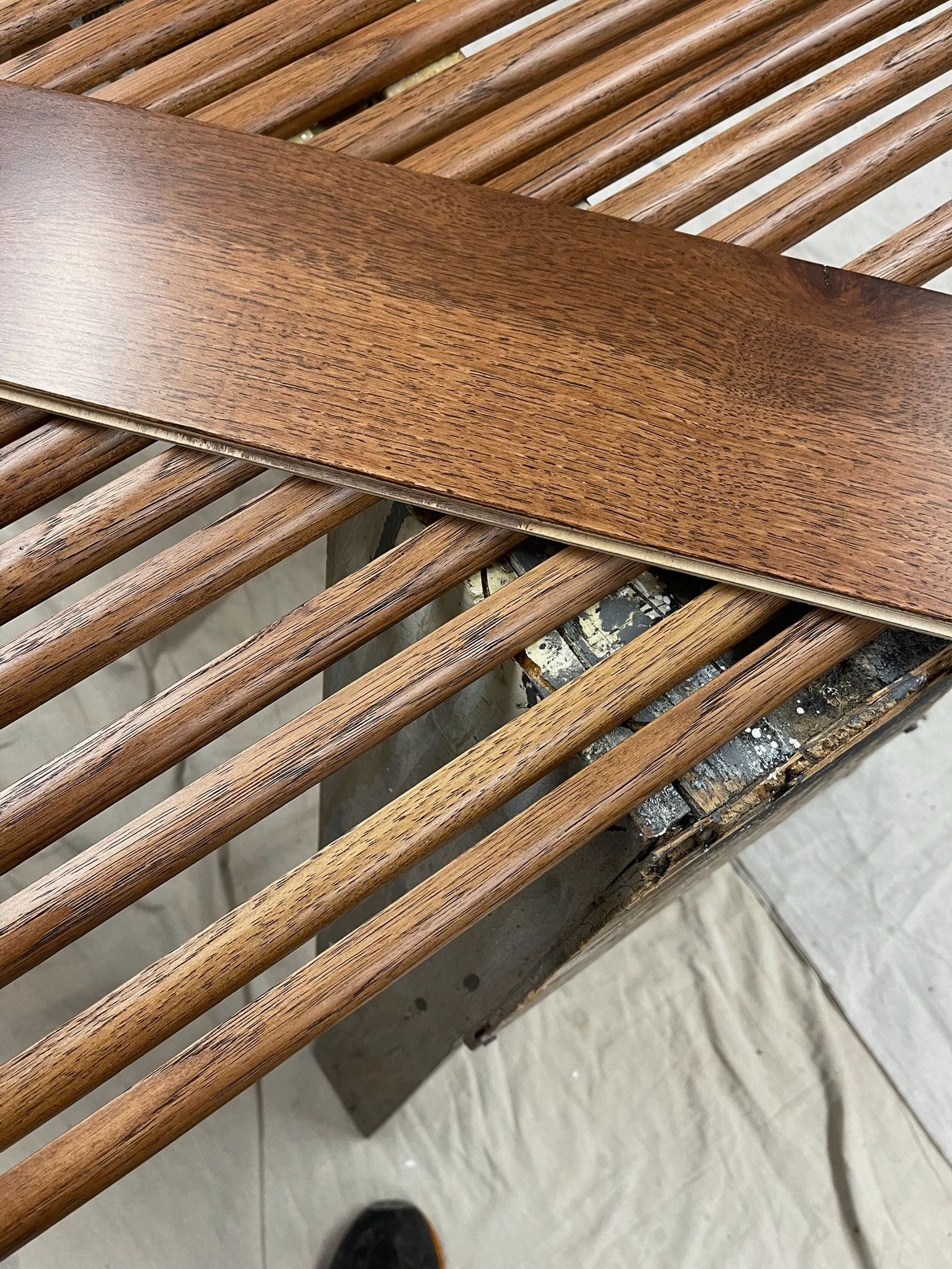 A person with a messy bun and bangs wears a green satin top and holds a straw hat against a bright, sunny sky.