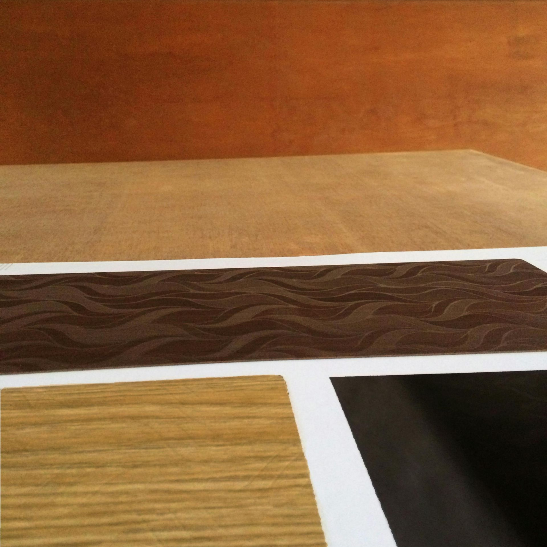 Various wood veneer samples in shades of brown, beige, and black arranged on a white surface.