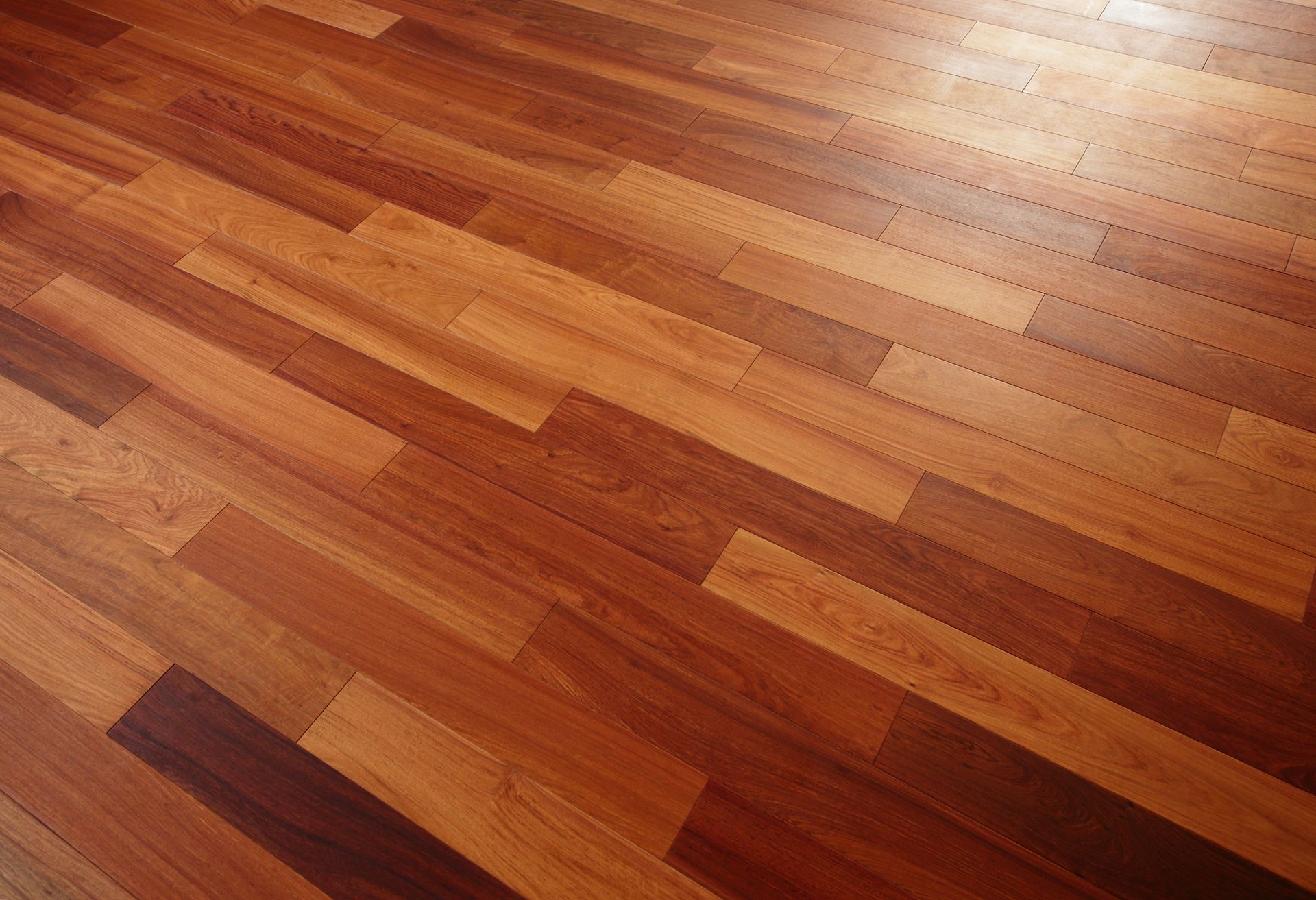 Polished hardwood flooring with varied brown tones and distinct wood grain patterns laid in a linear design.