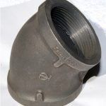 A close up of a metal pipe elbow on a white surface.
