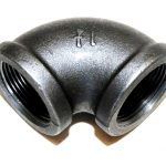 A close up of a black pipe elbow on a white background.