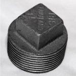 A close up of a black pipe plug on a white surface.