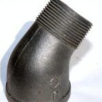 A close up of a black pipe elbow on a white surface.
