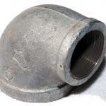 A close up of a metal pipe elbow on a white surface.