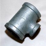 A close up of a galvanized pipe tee on a white surface.
