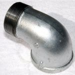 A close up of a metal elbow on a white surface.