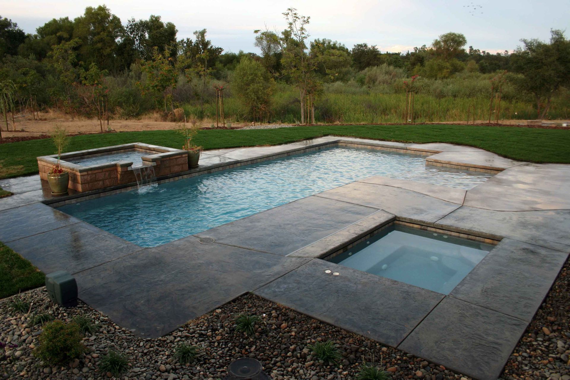 A large swimming pool with a hot tub next to it