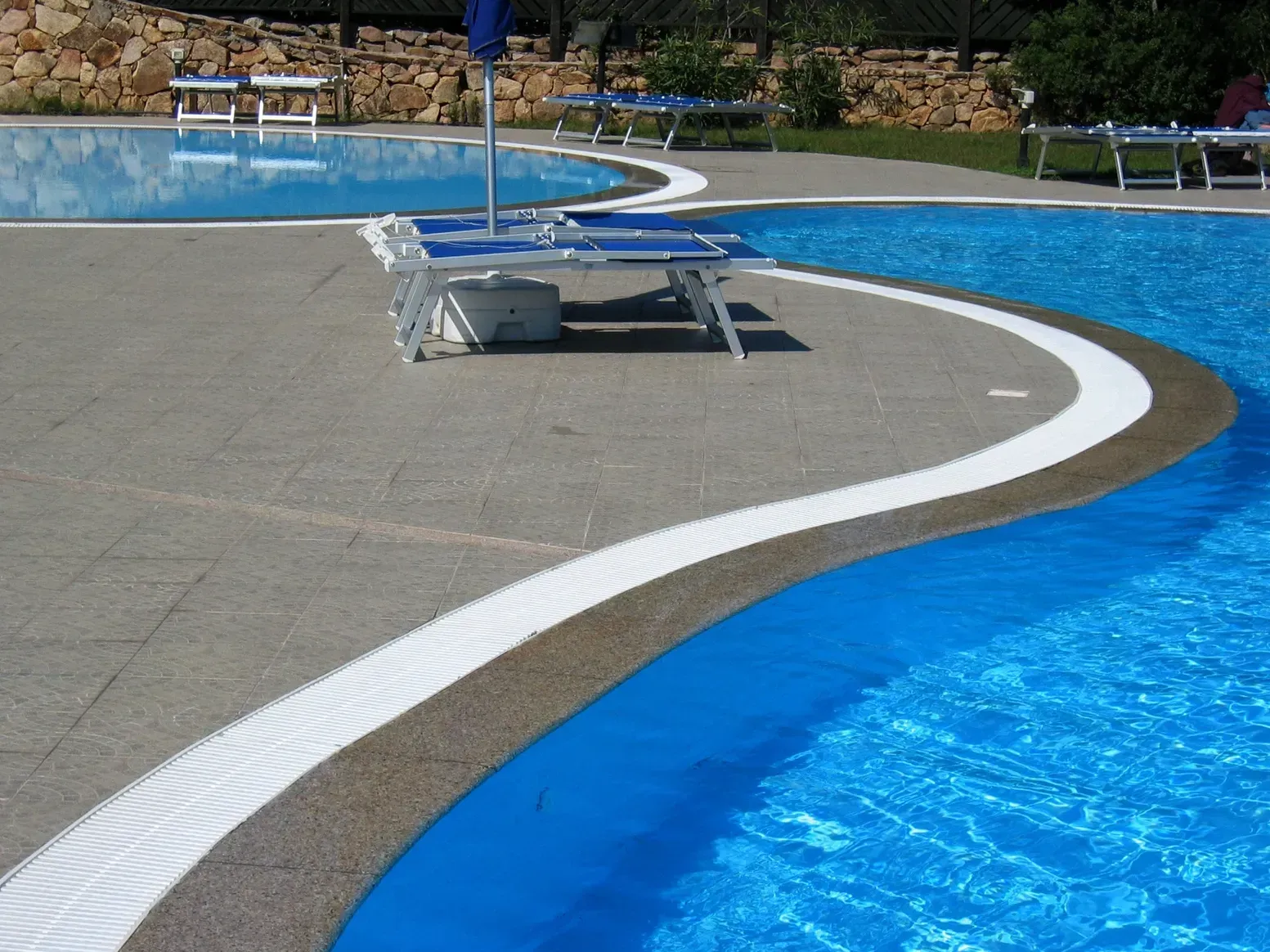 A large swimming pool with blue chairs and umbrellas