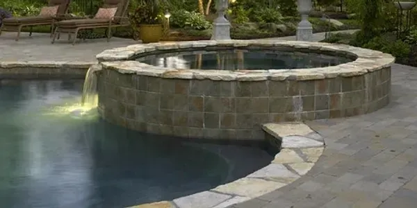 A swimming pool with a hot tub in the middle of it.