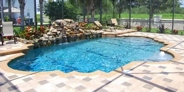 A large swimming pool with a waterfall in the backyard