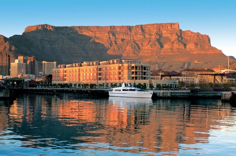 A boat is docked in a harbor with a mountain in the background.