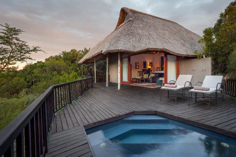 A thatched hut with a swimming pool in front of it