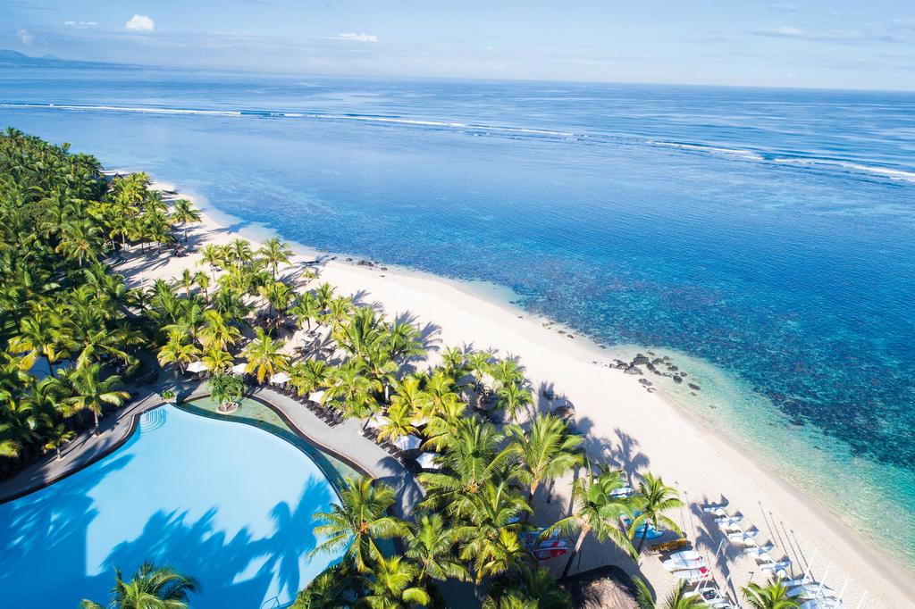 An aerial view of a tropical beach with palm trees and a swimming pool.