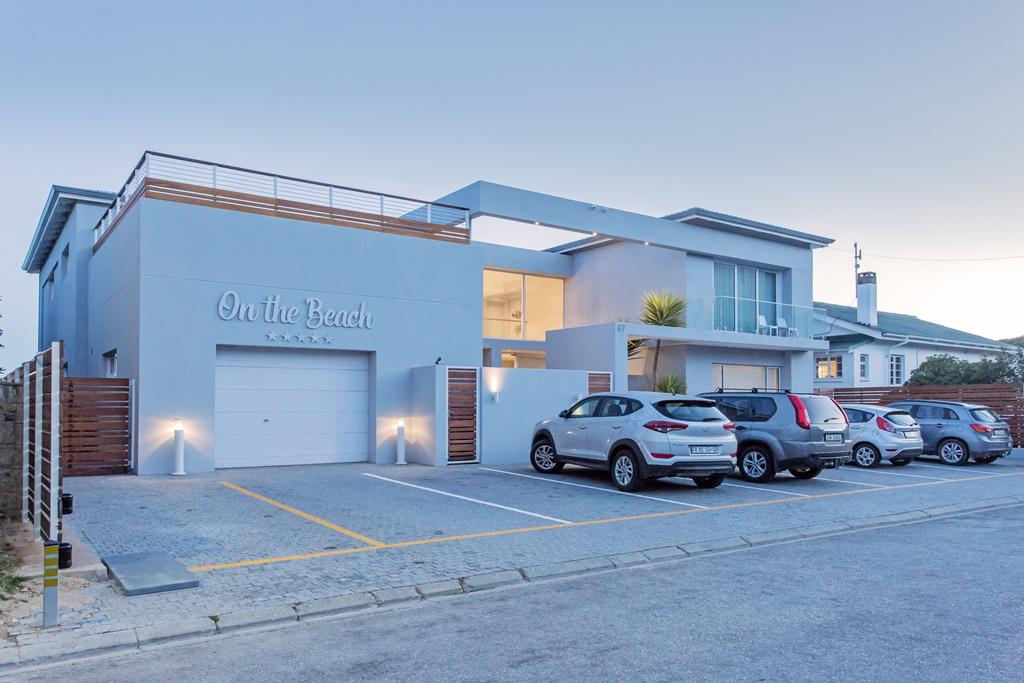 A row of cars are parked in front of a large house.