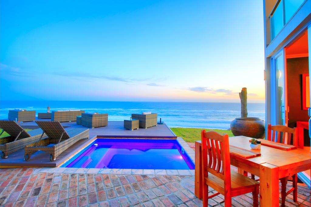 There is a swimming pool in the backyard of a house with a view of the ocean.