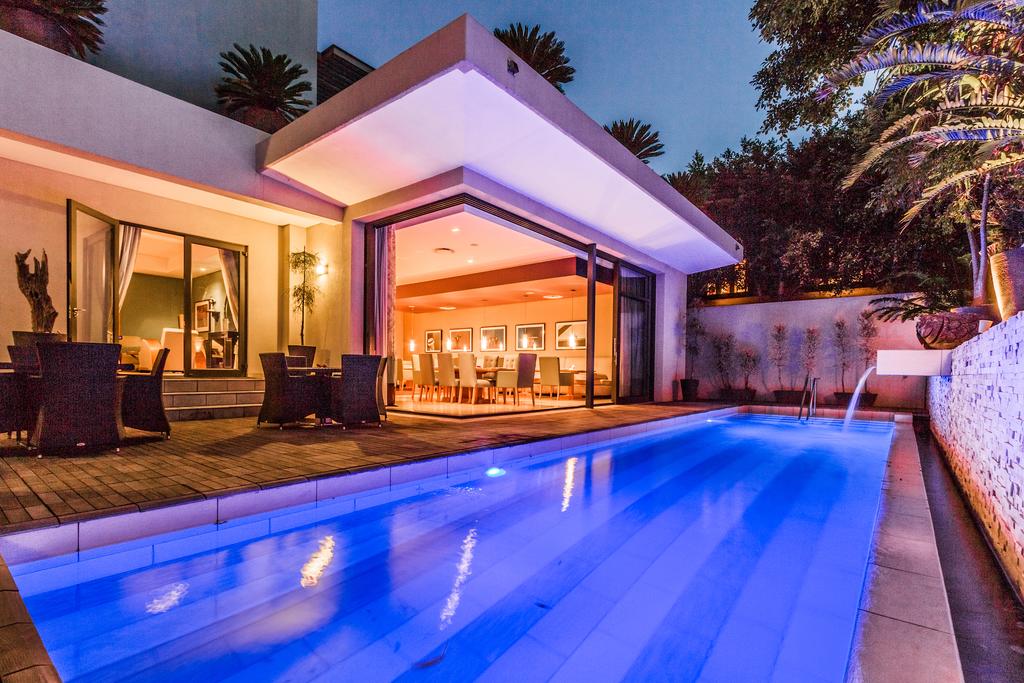 A large swimming pool is in the backyard of a house.