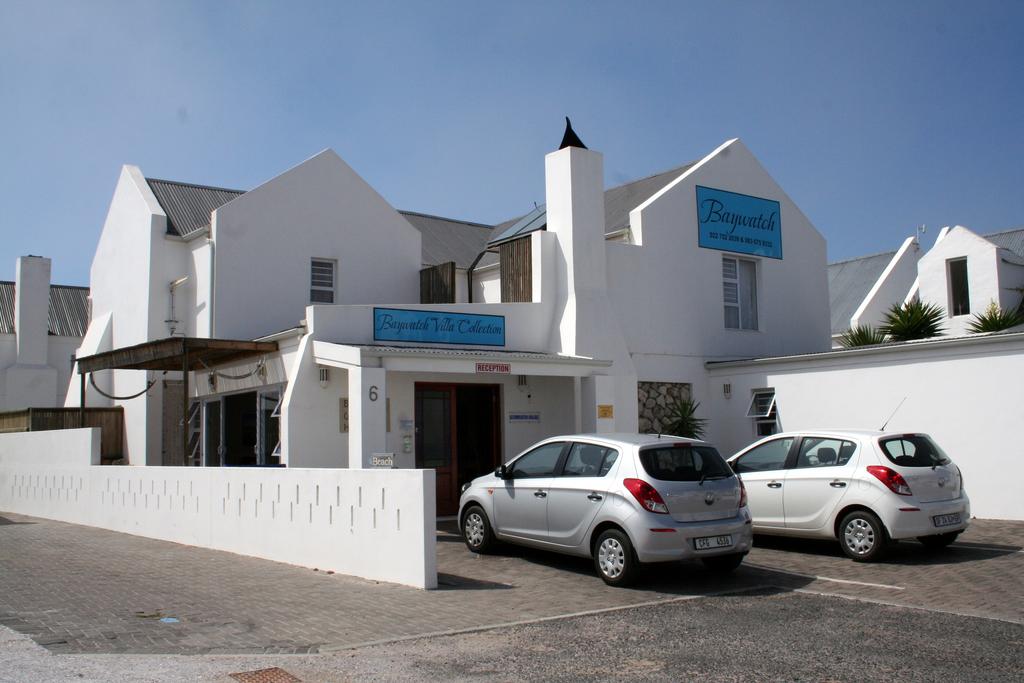 Two cars are parked in front of a white building