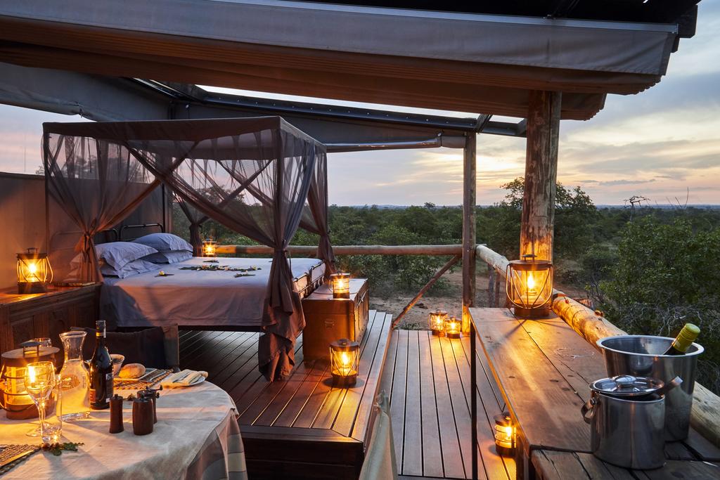 A canopy bed is sitting on top of a wooden deck.
