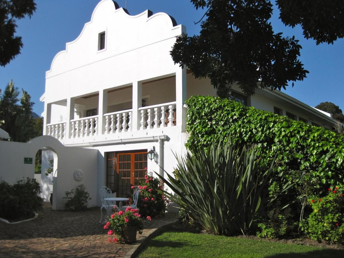A large white house with a balcony and flowers in front of it