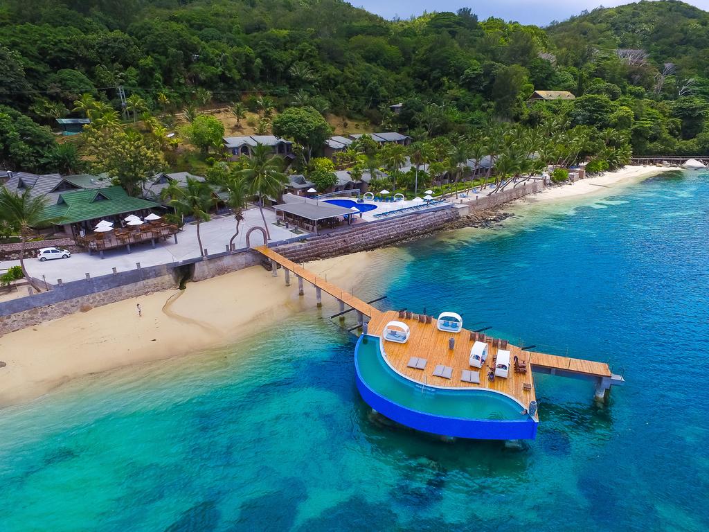 An aerial view of a beach with a dock and a boat in the water.