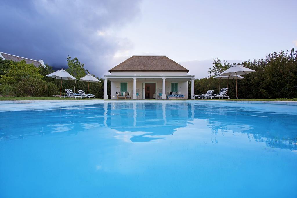 A large swimming pool with a white house in the background.