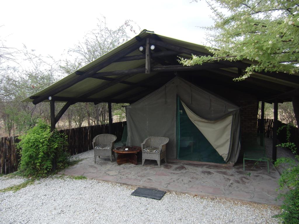 A tent is sitting under a covered area with chairs and a table