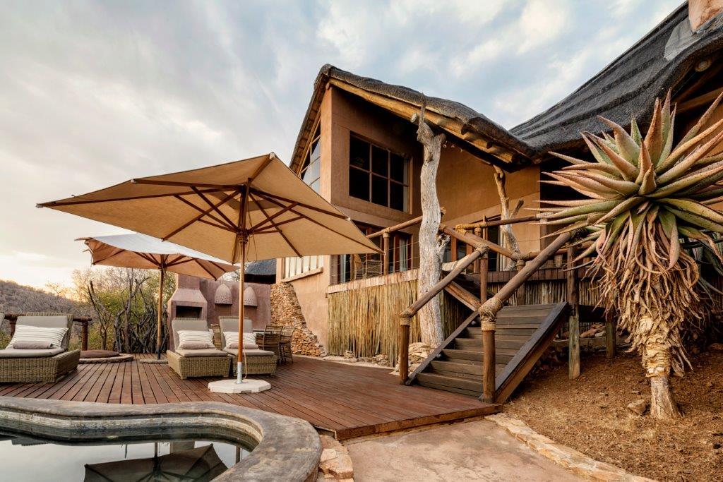 A large house with a pool and umbrellas in front of it