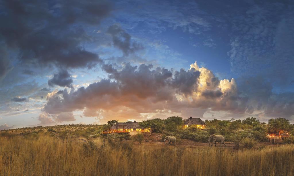 A house in the middle of a field with a cloudy sky in the background.
