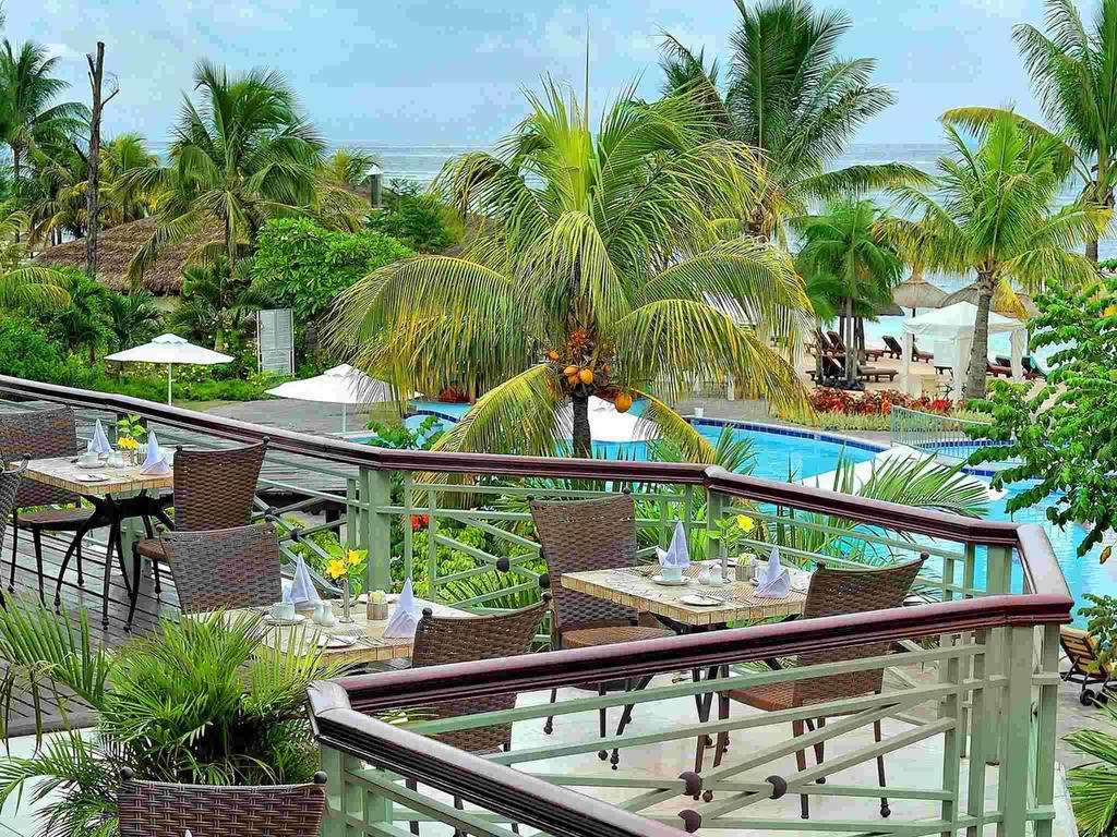 A balcony overlooking a swimming pool with tables and chairs.