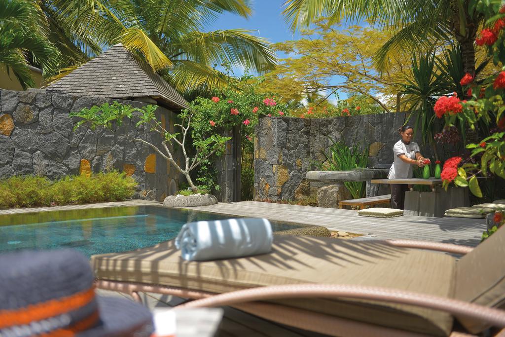 A man is pouring wine into a bottle next to a swimming pool.